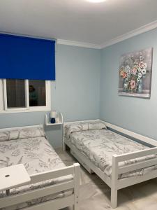 赫雷斯-德拉弗龙特拉Apartamento céntrico “Los Pajaritos” con garaje.的蓝色墙壁客房的两张床