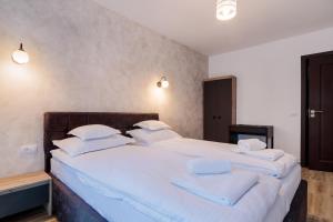克利默内什蒂Pensiunea Doro的卧室配有一张带白色床单和枕头的大床。