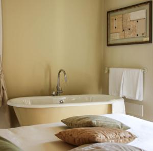 伊夫雷亚斯帕齐奥[比安科]酒店的浴室配有浴缸和床上的2个枕头。