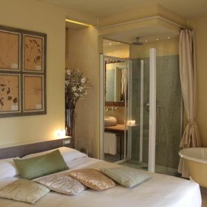 伊夫雷亚斯帕齐奥[比安科]酒店的一间卧室配有一张床,浴室设有浴缸