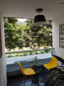 麦德林Hotel Aura Medellin的一间设有两张黄色椅子和窗户的房间