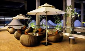 吉大港Radisson Blu Chattogram Bay View的餐厅配有沙发、桌子和雨伞