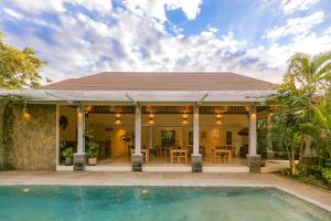 努沙杜瓦La Berceuse Resort and Villa Nusa Dua by Taritiya Collection的一座房子前面设有游泳池