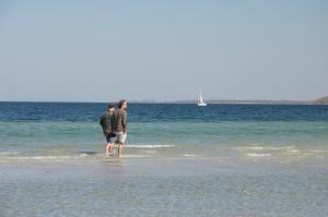 赫亨基尔兴Bungalows Ostseequelle的两个人在海滩上水中散步