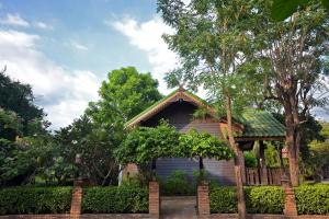 素可泰Thai Thai Sukhothai Resort的一座小房子,带栅栏和树木
