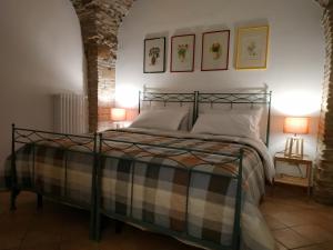 韦诺萨Bed and Breakfast In Piazza Orazio的一间卧室配有一张带两盏灯的床,墙上有两张照片