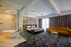萨诺克Hotel Wiki Sanok Events & Bowling的带浴缸、床和沙发的酒店客房