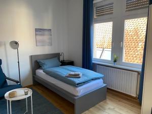 埃特林根Gästehaus Windheim Ettlingen Stadt的一间卧室配有一张床和一把椅子,还有两个窗户