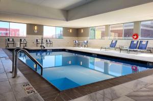 EnidGLō Best Western Enid OK Downtown - Convention Center Hotel的一个带蓝色椅子和桌子的游泳池