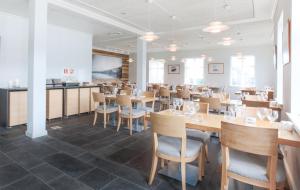Fáskrúðsfjörður东部峡湾福斯酒店的用餐室配有木桌和椅子