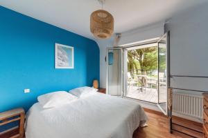 克拉斯卡诺特Les Chardonnerets - Maison contemporaine Vue Mer的一间蓝色卧室,配有一张床和一个阳台