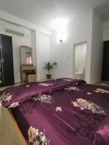 HithadhooThe Rose Garden House, Addu City, Maldives的卧室配有床上的紫色毯子