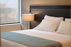 麦德林麦德林埃斯特拉公寓酒店的一间卧室配有带白色枕头和灯的床