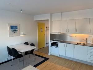 努克Nuuk Hotel Apartments by HHE的厨房配有白色橱柜和桌椅