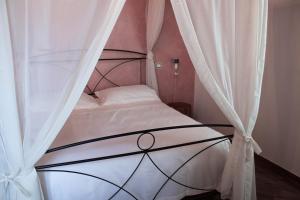比萨Fattoria L'Olmetto的卧室配有带白色窗帘的天蓬床