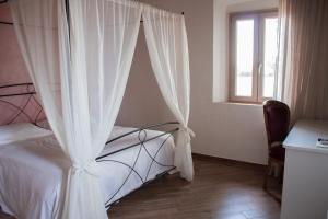 比萨Fattoria L'Olmetto的卧室配有带白色窗帘的床和窗户。