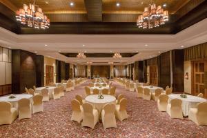 卡尔贾特Radisson Blu Plaza Resort & Convention Centre Karjat的宴会厅配有桌椅和吊灯