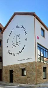 穆希亚Pousadas Mariñeiras,sl - AT "Camiño da Barca"的建筑的侧面有标志