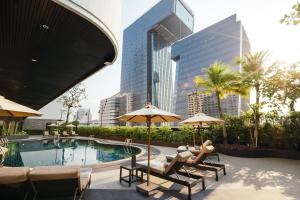 曼谷Grand Fortune Hotel Bangkok的城市里一个带椅子和遮阳伞的游泳池