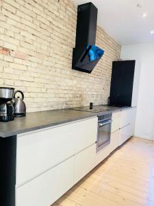 奥尔堡aday - Central cozy and bright apartment的厨房配有白色橱柜和砖墙
