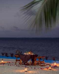 吉汶瓦Moja Tuu The Luxury villas & Nature Retreat的海滩上的一张桌子,上面有蜡烛和灯光