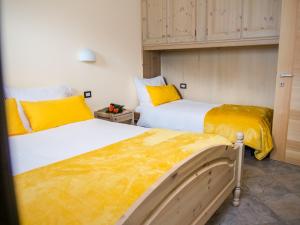 博尔米奥Residence Pedranzini的黄色和白色的客房内的两张床