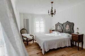 Rocca D'ArazzoLa Corte di Lu的一间卧室配有一张床、一把椅子和一个吊灯。