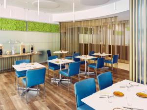 梅斯特诺富特威尼斯梅斯特卡斯特拉纳酒店的用餐室配有白色的桌子和蓝色的椅子