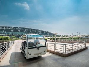 广州Pullman Guangzhou Baiyun Airport - Canton Fair Free Shuttle Bus & Official Registration Agency的驾驶在桥上的小型白色高尔夫球车