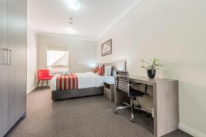悉尼Best Western Plus Camperdown Suites的酒店客房配有一张床、一张桌子和一把椅子。