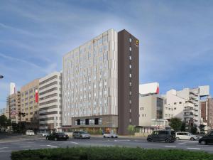 高松Comfort Hotel Takamatsu的停车场内有车辆停放的高楼