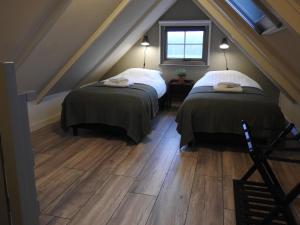 BeilenVakantiehuis Bed en Breakfast in de Tuin的阁楼间设有两张床,铺有木地板