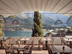 巴利恩Troulis Apart-Hotel的一间带桌椅并享有水景的餐厅