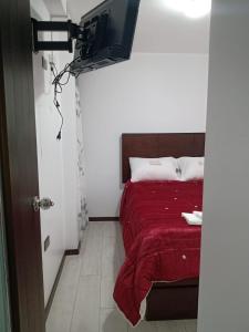 HuancavelicaPYMABET的一间卧室配有一张带红色毯子的床和一台电视。