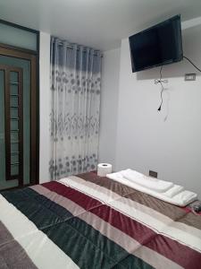 HuancavelicaPYMABET的卧室配有一张床铺,墙上配有电视