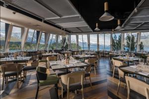 皇后镇Rydges Lakeland Resort Queenstown的餐厅配有桌椅,位于山脉的背景中