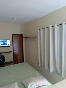 卡博迪圣阿戈斯蒂尼奥Kitnet 2,vista fantastica的一间卧室配有床、窗帘和电视