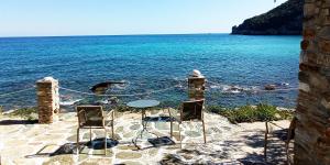 KeramídhionPilion-Unique House at the Aegean Sea的海滩上摆放着一张桌子和两把椅子