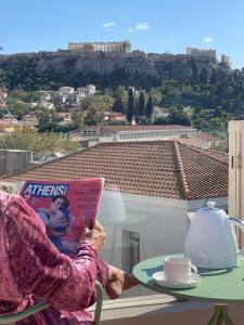 雅典L'Avventura Athens的坐在桌子上一边读书一边喝咖啡的人