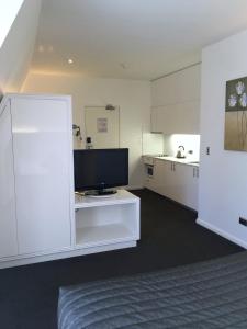 悉尼The Social Hotel, Sydney的带电视的客厅和白色厨房。
