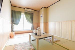 松山渡高别墅式酒店的一间设有桌子和窗户的客房