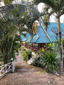 Ban Pa Waiเพชร รีสอร์ท นครไทย-Phet Resort, Nakhonthai的一座拥有蓝色屋顶和棕榈树的建筑