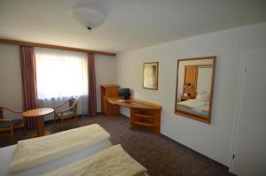 米特尔贝格韦德斯坦因艾尔彭酒店的酒店客房带一张床、一张书桌和一面镜子