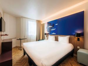 尼斯尼斯机场宜必思尚品酒店的酒店客房设有一张白色大床和蓝色的墙壁。