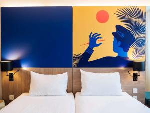 尼斯尼斯机场宜必思尚品酒店的两张位于酒店客房的床,墙上挂着一幅画