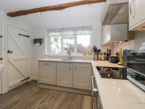 谢伯恩Snowdrop Cottage的厨房配有白色橱柜和水槽