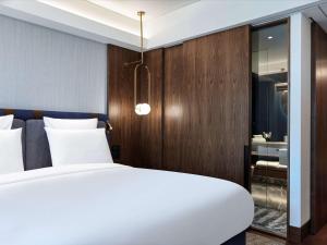 雅典Athens Capital Center Hotel - MGallery Collection的卧室配有白色的床和木墙
