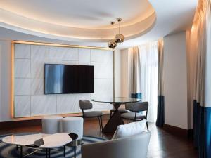 雅典Athens Capital Center Hotel - MGallery Collection的客厅配有桌椅和电视。