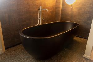 Albosaggia泰拉德尔索勒农庄旅馆的浴室设有黑色浴缸,光线充足