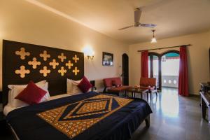 拉杰果德Heritage Khirasara Palace的一间卧室配有一张带蓝色毯子和红色枕头的床。